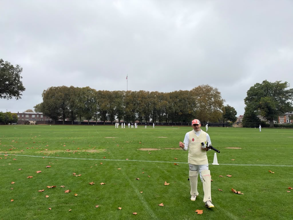 A GCC batter holding his gear on the field