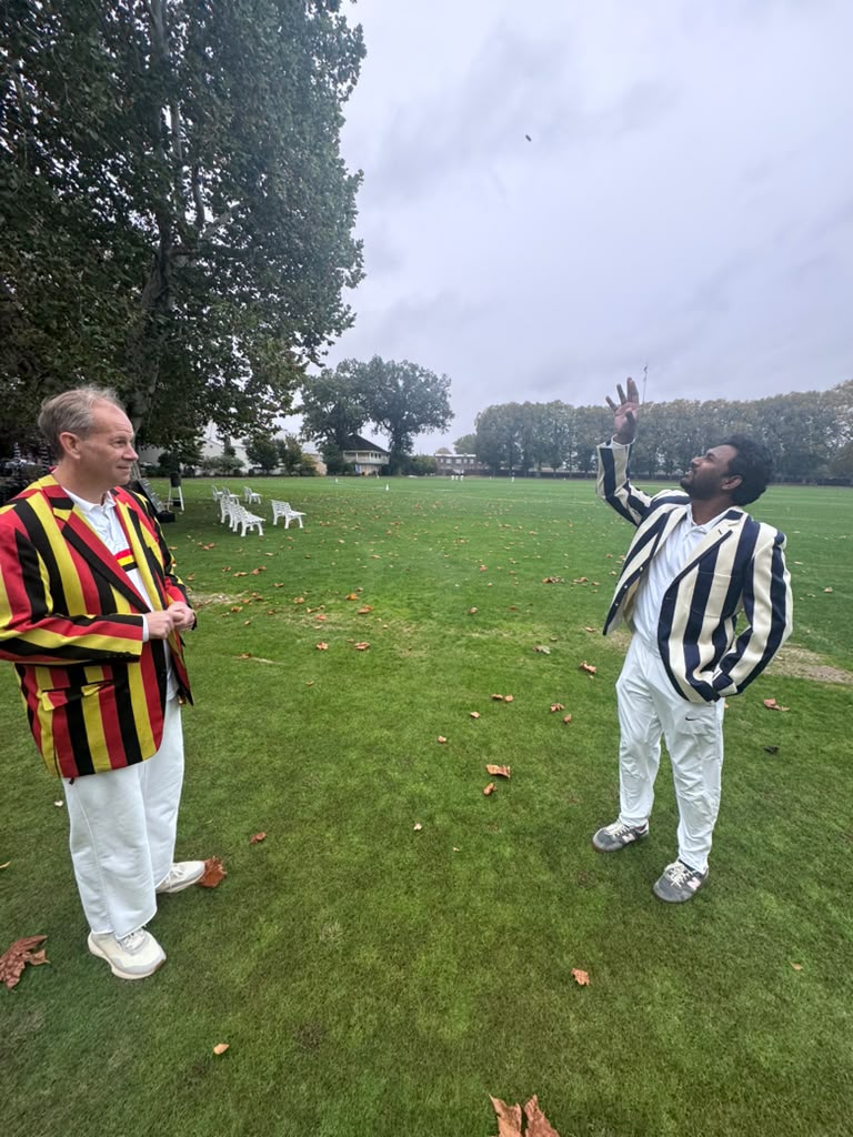 Two captains in club blazers shaking hands at the toss before the match