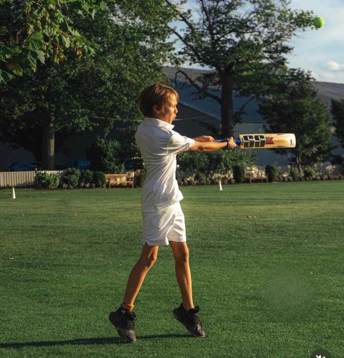 A young player hitting a tennis ball on the GCC lawn
