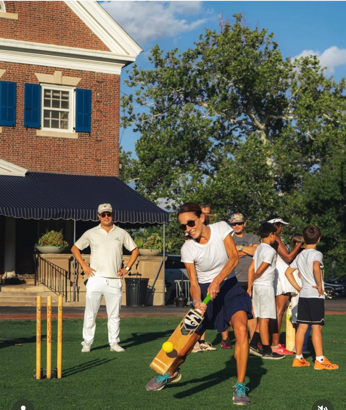 A player striking a tennis ball in front of the Germantown Cricket Club clubhouse